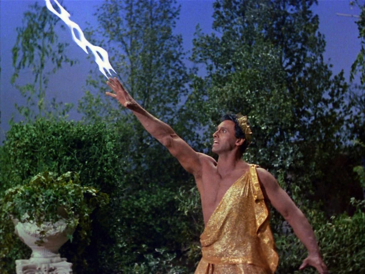 Star Trek still of the god Apollo in a gold tunic hurling lightning from his hand