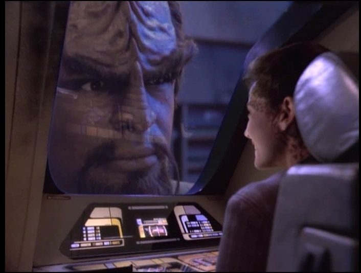 Star Trek still of a Klingon's huge face filling a viewscreen as a crewwoman looks on