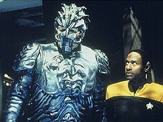 Star Trek: Voyager still of Tuvok beside a towering silver armoured alien