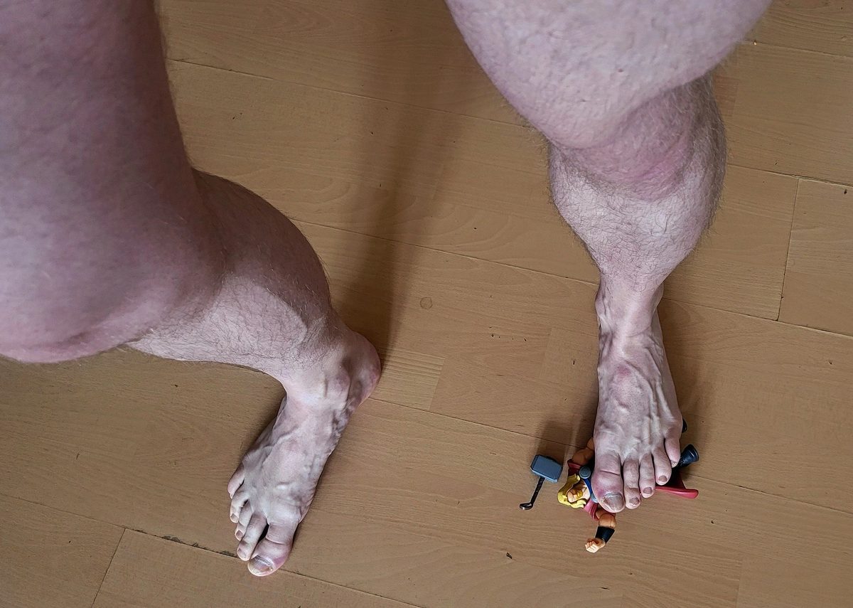 Giant bare feet on a wooden floor with tiny figures beside the toes
