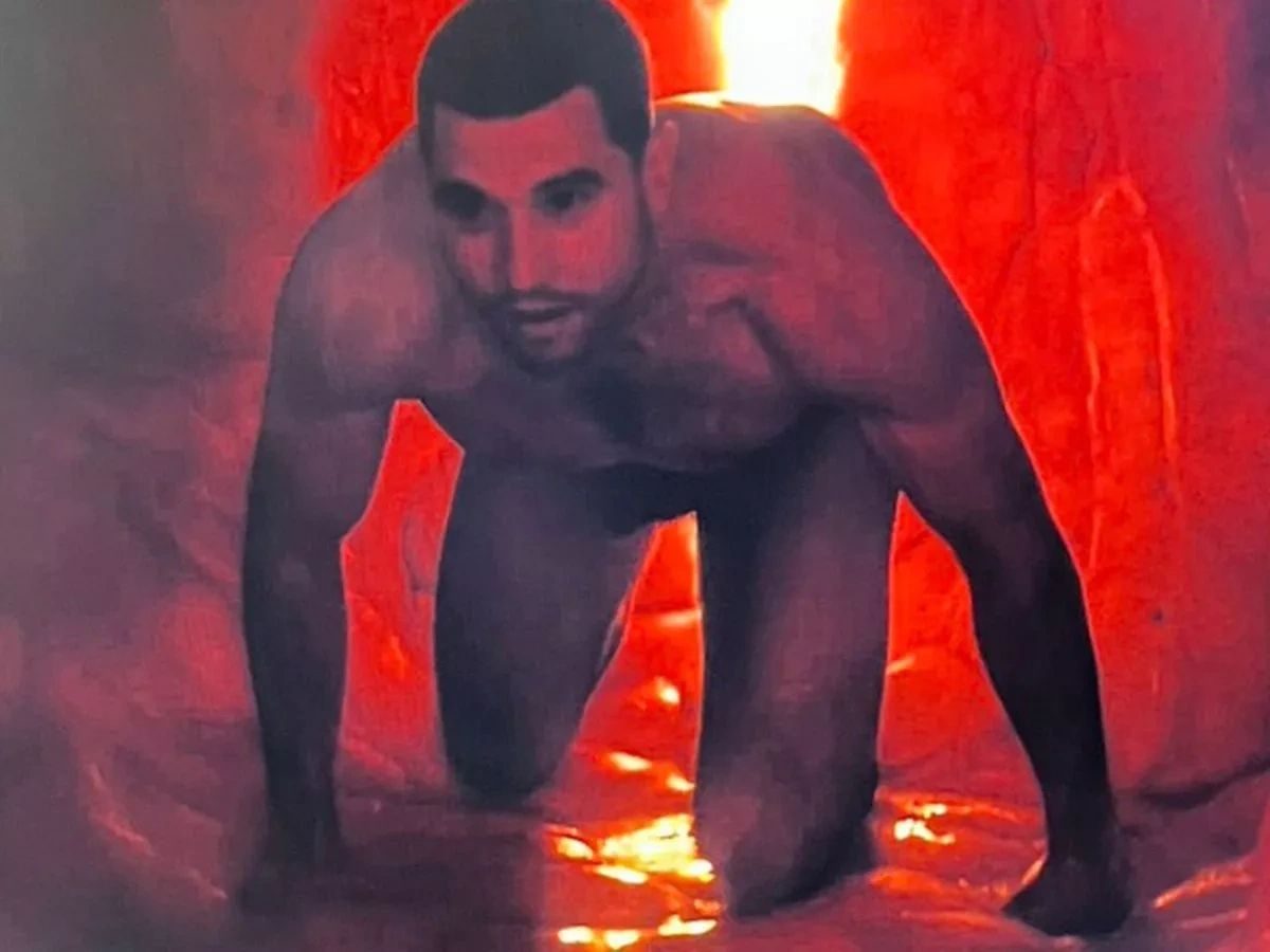 A naked man crawling on all fours through a glowing red cave