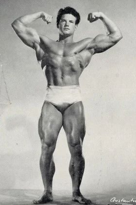Vintage photo of Steve Reeves flexing his biceps in white posing trunks