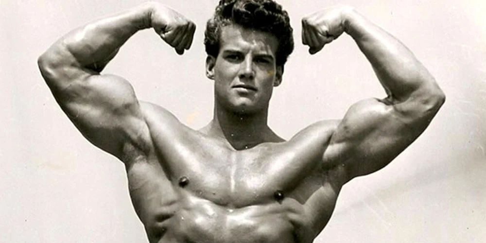 Vintage black and white photo of Steve Reeves flexing both biceps