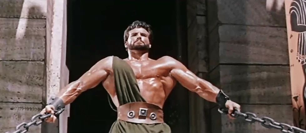 Film still of Steve Reeves as Hercules, chained between two pillars