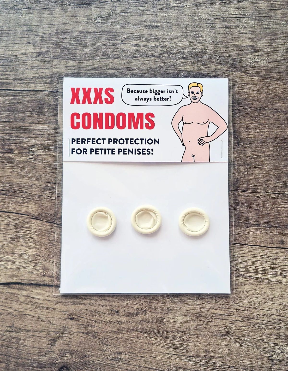 Novelty pack of XXXS condoms on a wooden table, a cartoon naked man on the label